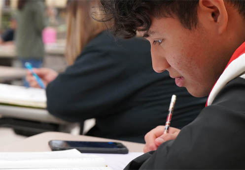 A NOCE student look down at his notebook, writing his notes.