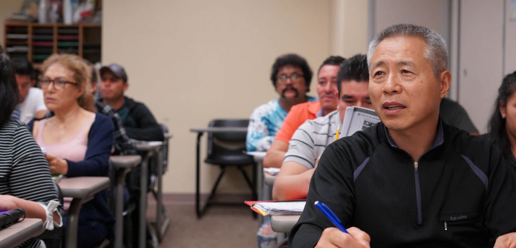 A photo of a row of ESL students taking notes in class.