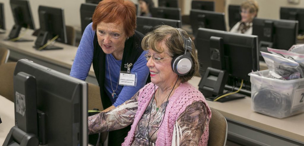 A NOCE instructor helping an older student use the computer.