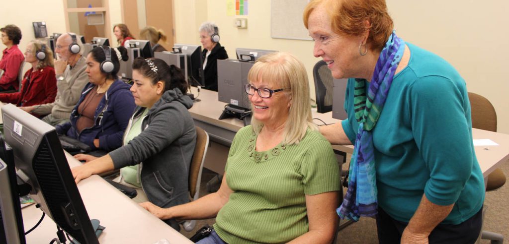 A NOCE instructor helping an older adult student to use the computer.