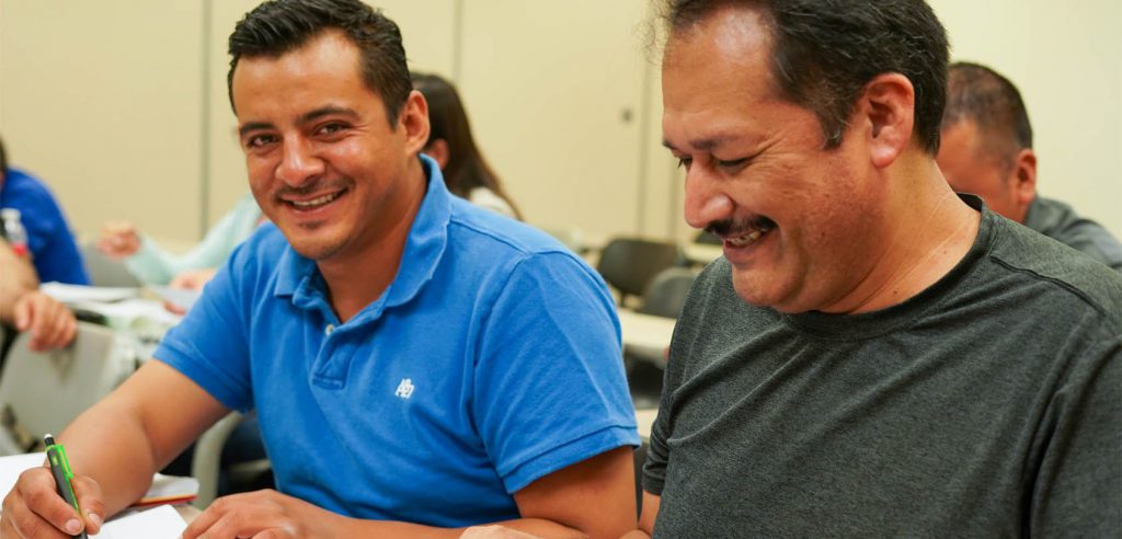 A photo of two male English as a Second Language (ESL) students smiling in class.