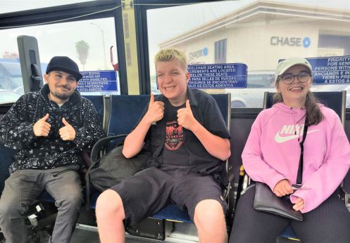 Three dss students sitting in an OCTA bus, smiling and posing with their thumbs up.