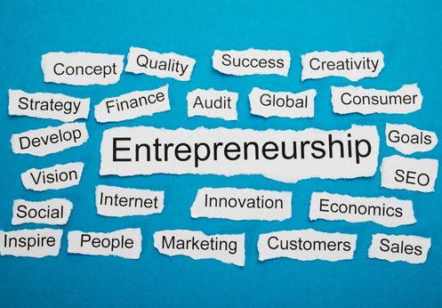 A blue background with strips of white paper with words like Entrepreneurship, goals, innovation, etc.